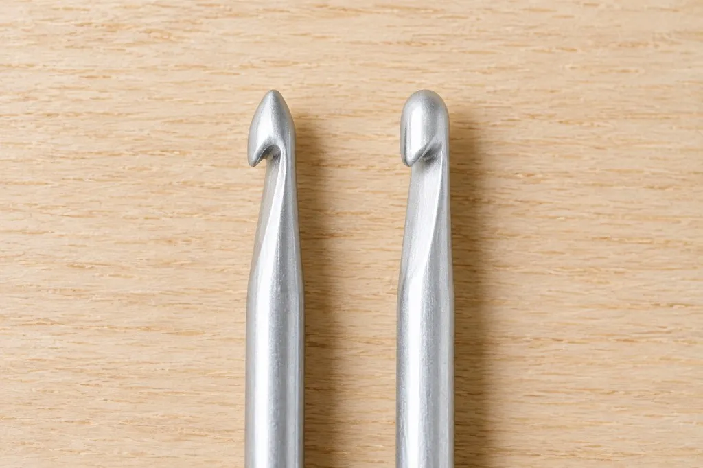 Two crochet hook heads side by side, one with a pointed tapered tip and one with a flat inline head